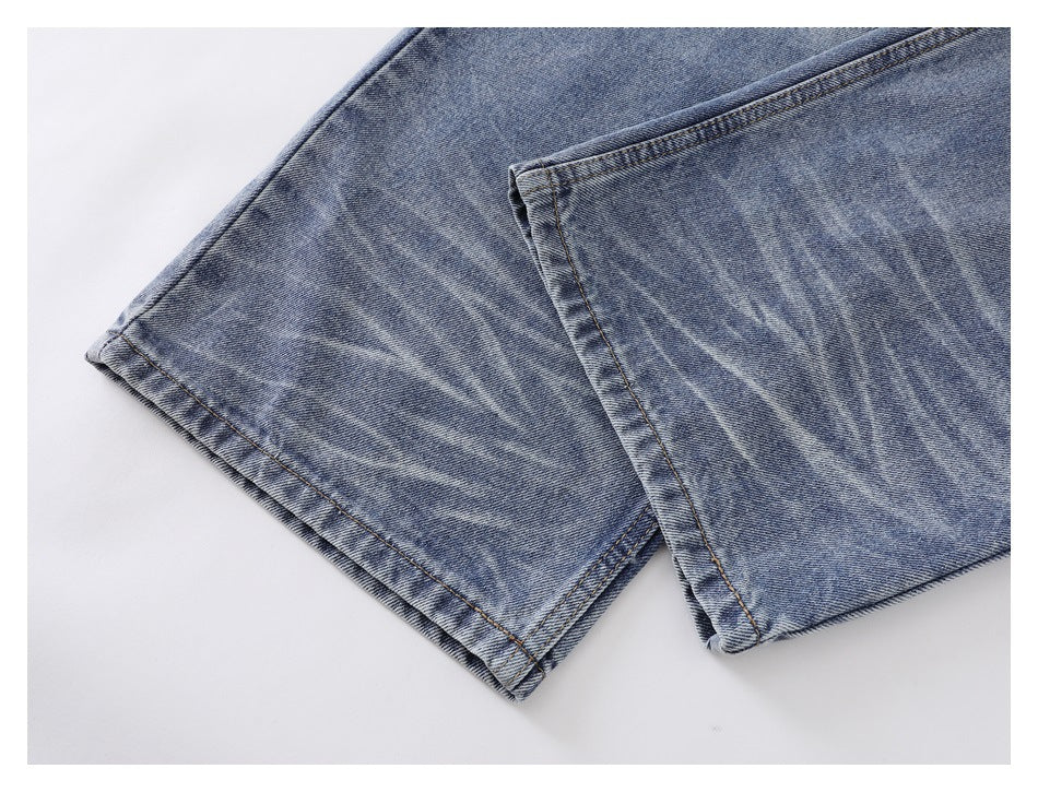 Close-up of faded blue jean hems with double stitching and a worn finish.