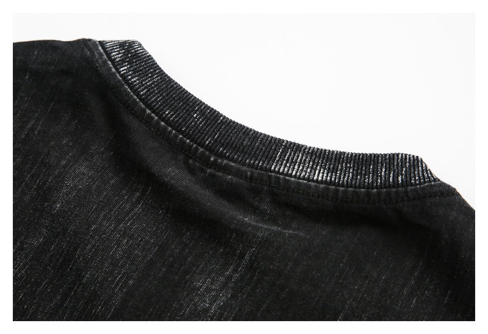 Close-up of a black garment’s ribbed crew neckline and shoulder seam.