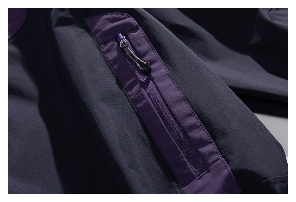 Close-up of a purple sleeve zipper with a corded pull on the dark navy jacket.