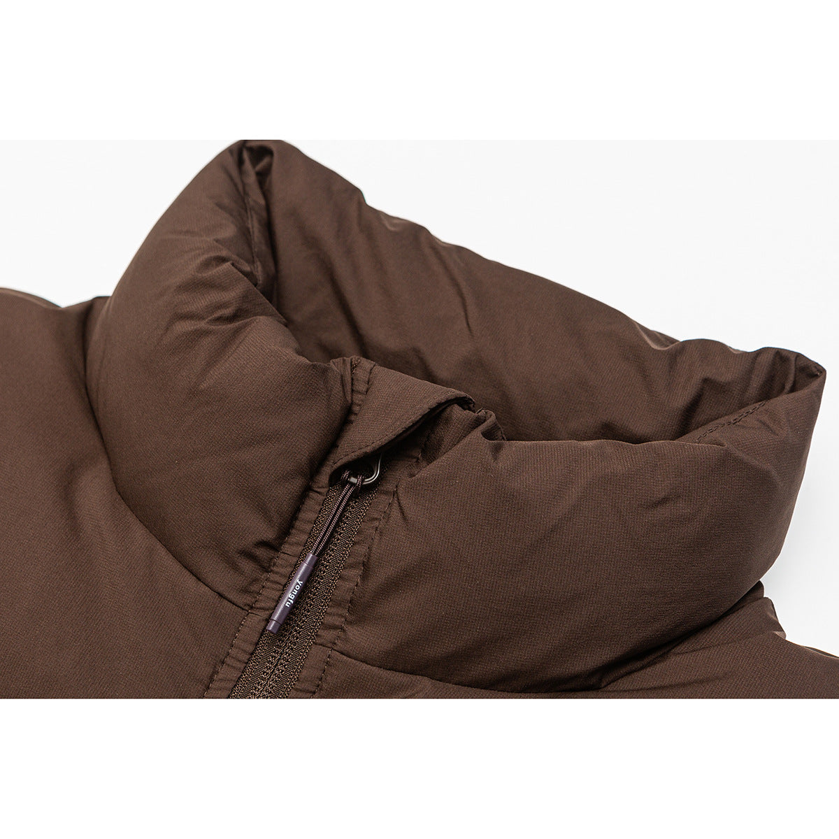 Close-up of a brown padded jacket's high collar and front zipper with a small zipper pull.