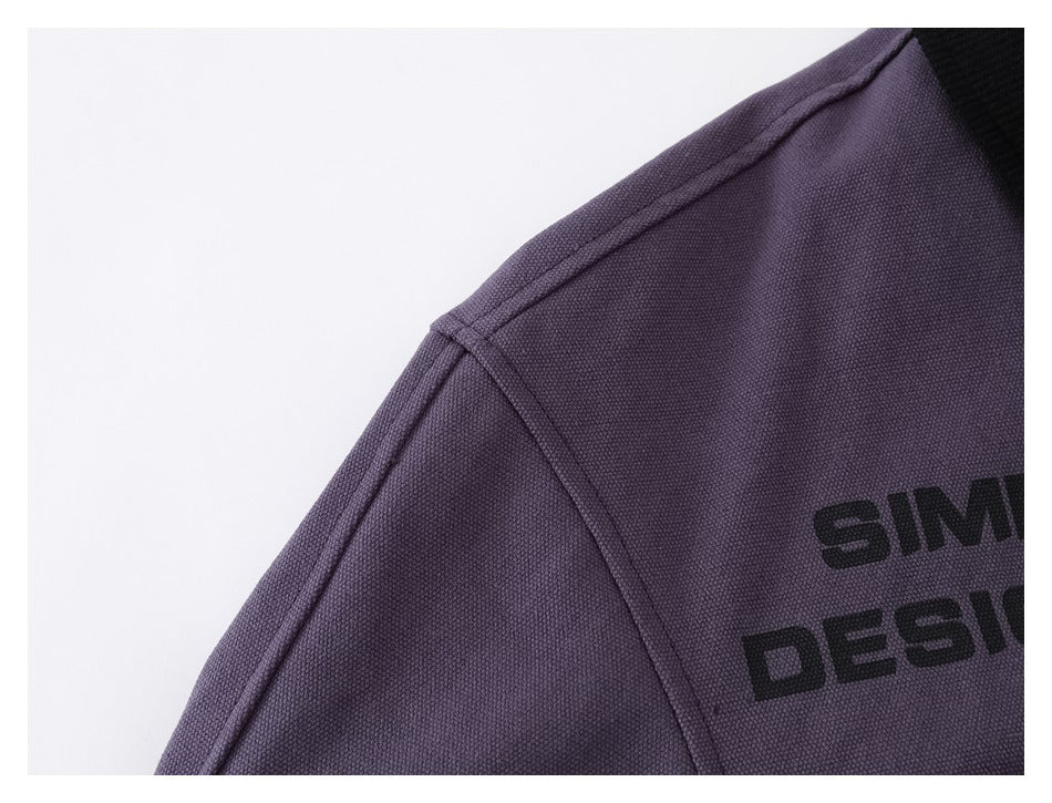 Close-up of the purple jacket's shoulder seam and textured fabric, with partial black chest lettering.
