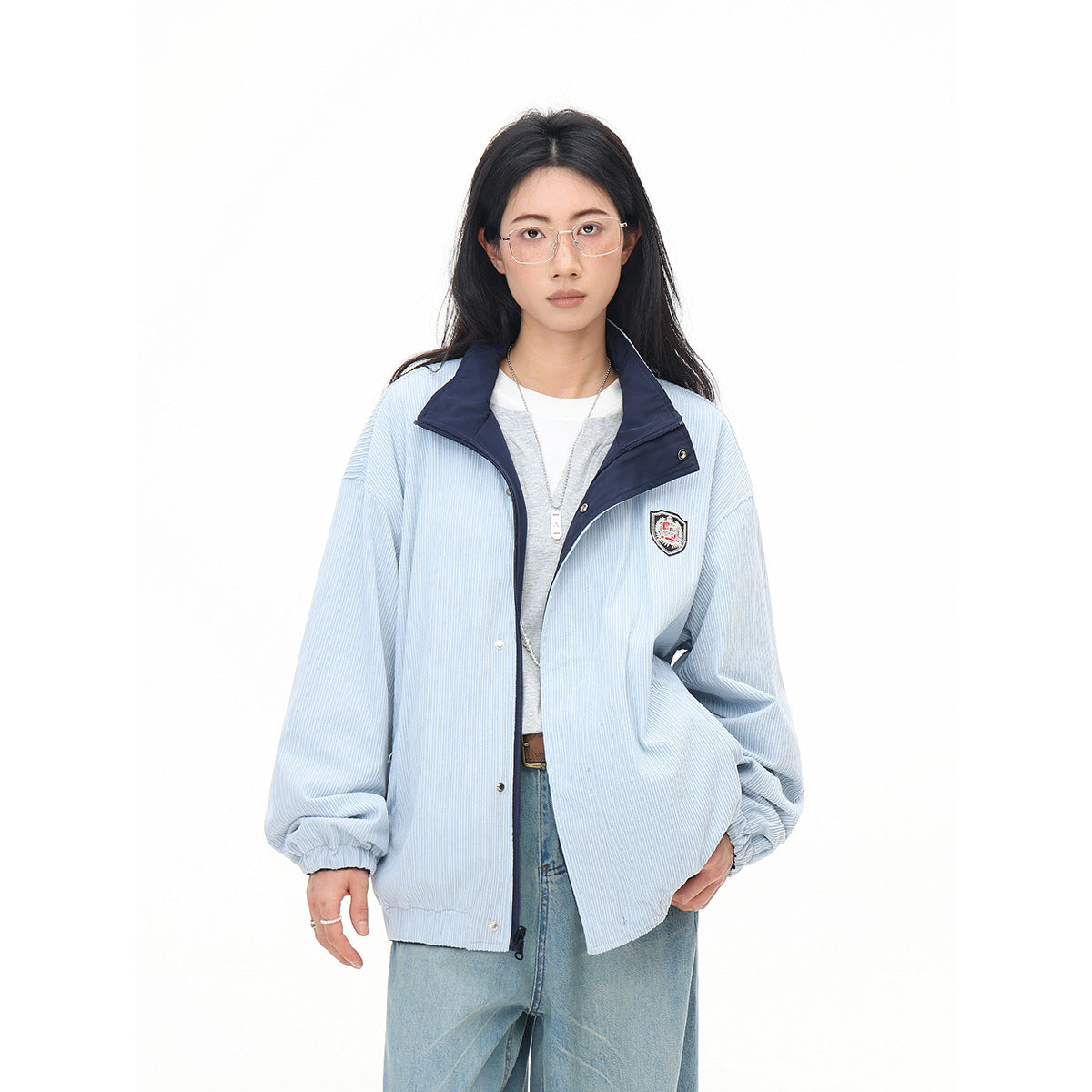 Closer view of a model wearing an open pale blue pinstriped jacket with a navy collar and chest patch.