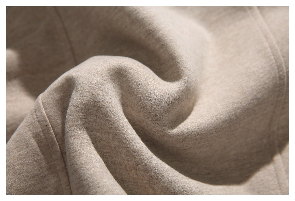 Close-up of softly folded beige coat fabric with a visible stitched seam.