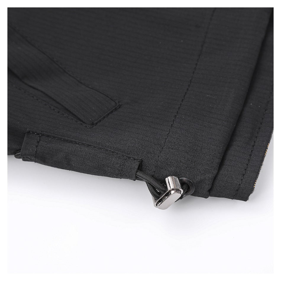 Close-up of a black garment's hem with an elastic drawcord and metal toggle.