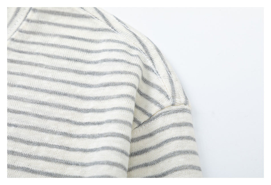 Close-up of the shoulder seam on a cream top with thin gray stripes.