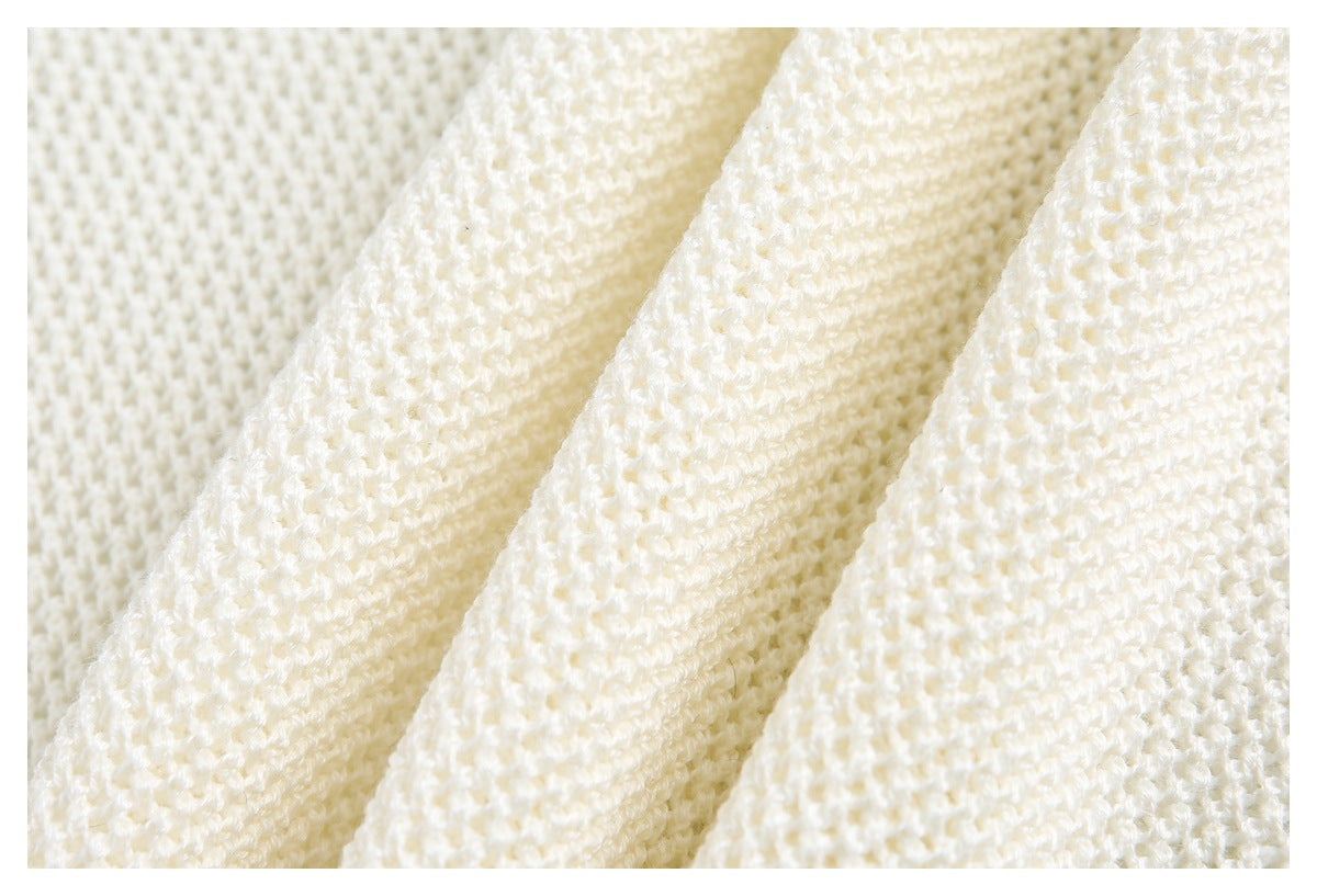 Close-up of cream-colored knit fabric with a textured open stitch pattern.