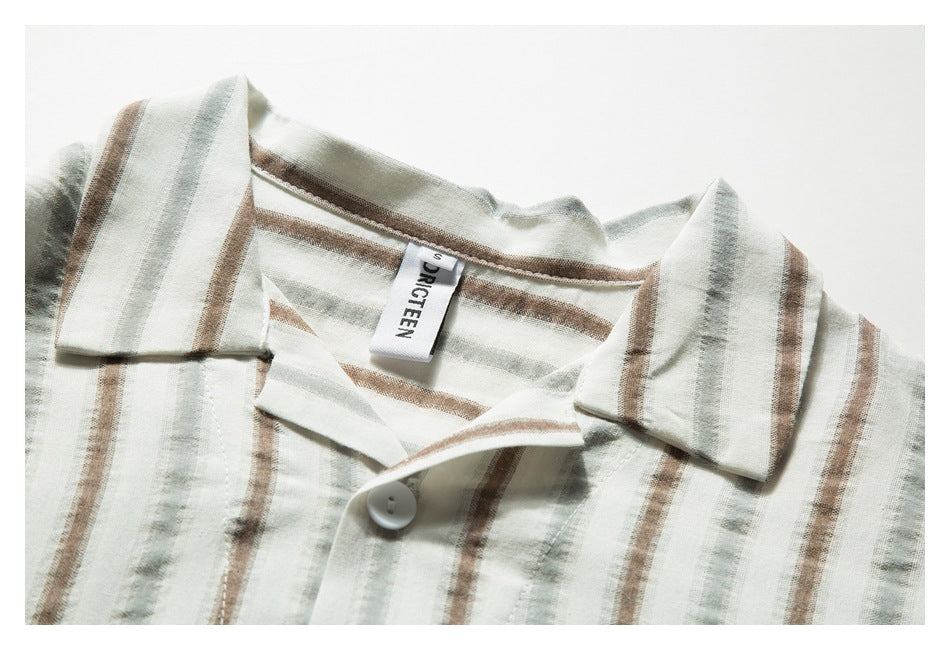 Close-up of a cream striped shirt's open collar and neckline with one white button and a sewn-in label.