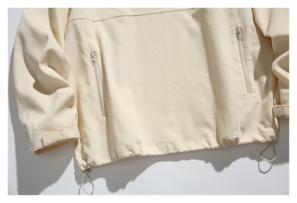Close-up of the cream jacket’s lower front, showing two vertical zip pockets and adjustable hem cords.