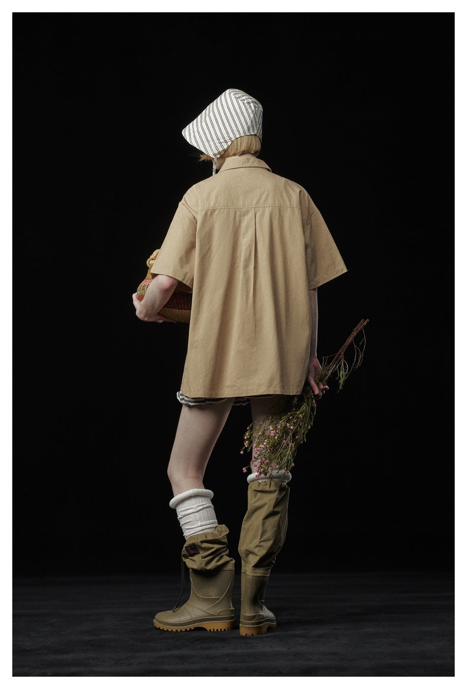 Back view of a model wearing a loose tan short-sleeve shirt with a center back pleat.