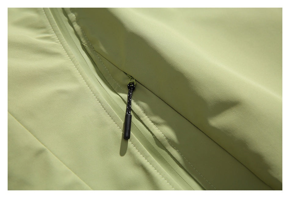 Close-up of a black zipper pull on a pale olive jacket pocket.