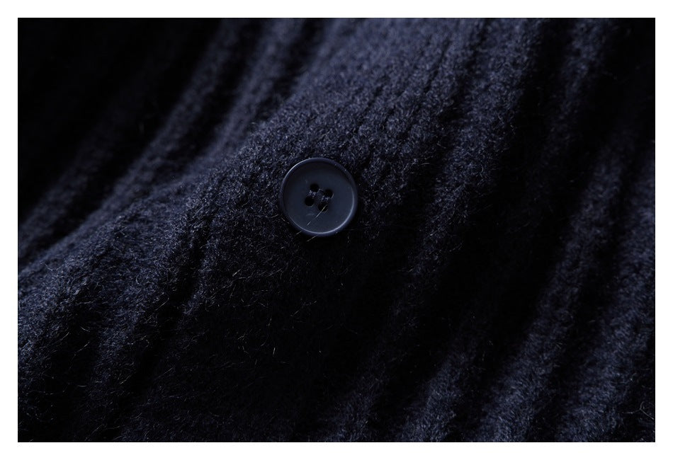 Close-up of a dark button against the fuzzy ribbed knit of a navy cardigan.