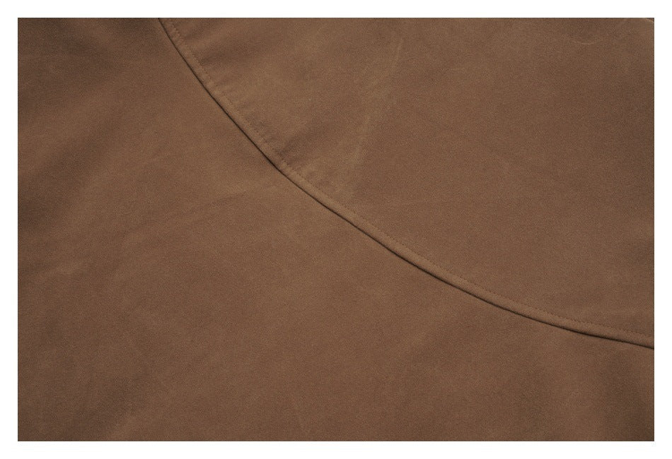Close-up of smooth brown jacket fabric with a curved stitched seam.