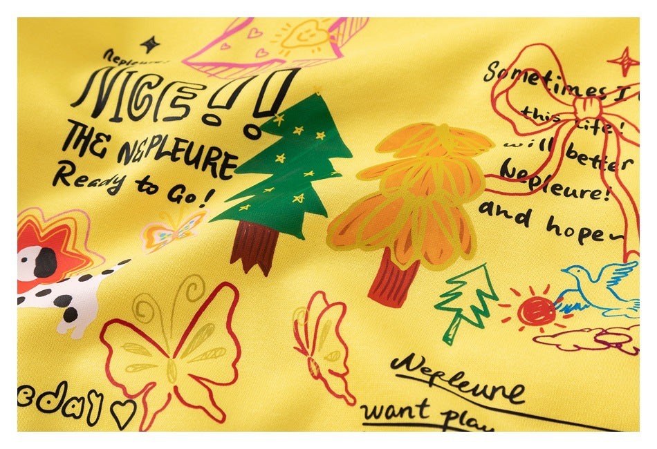 Close-up of the yellow sweatshirt's colorful illustrated print with trees, butterflies, a dog, and English lettering.