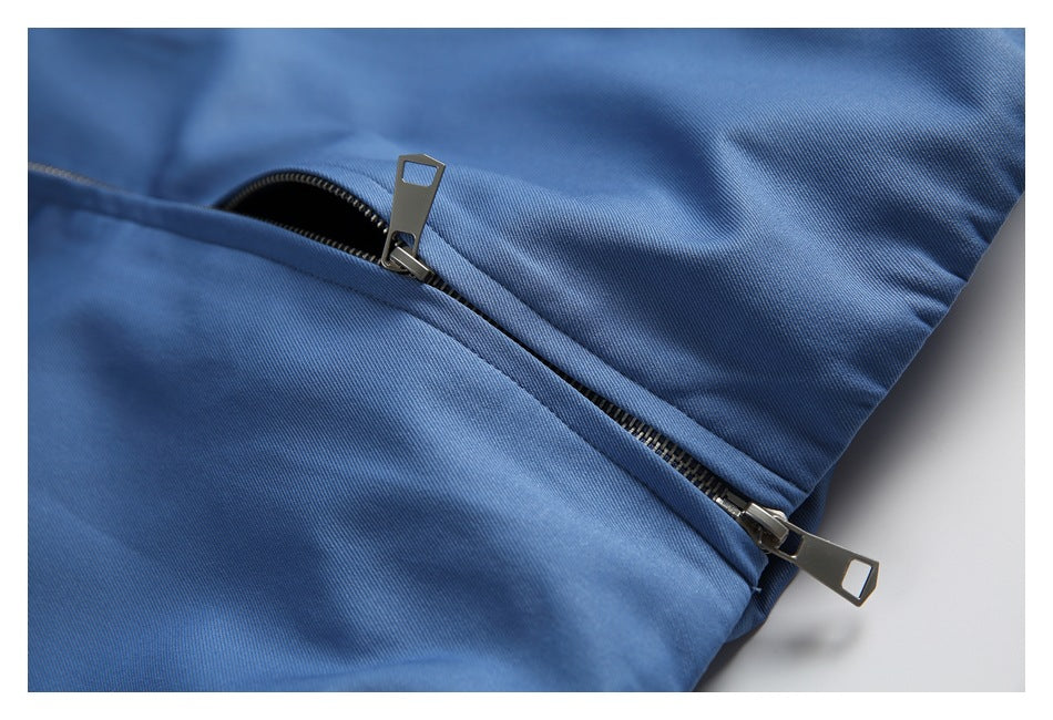 Close-up of a metal zipper with two pulls on blue fabric.