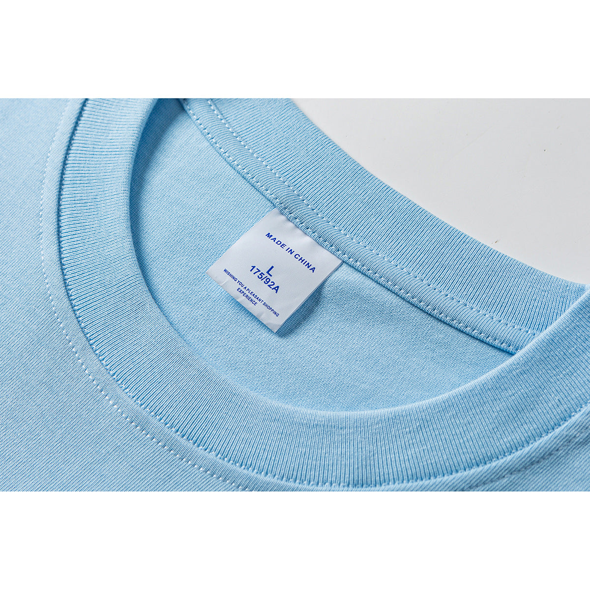 Close-up of a light blue T-shirt neckline and sewn-in label marked size L and Made in China.