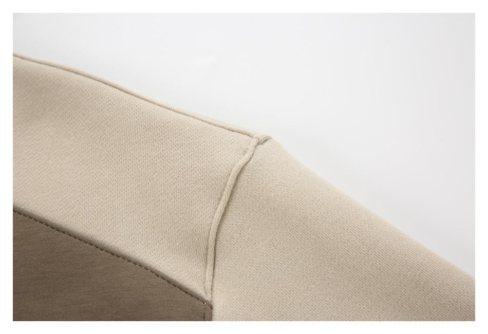 Close-up of a beige sweatshirt shoulder seam with a taupe colorblock panel.