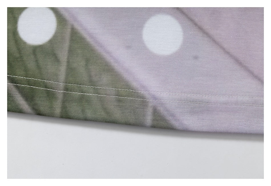 Close-up of a stitched hem on green and lilac printed fabric with large white dots.