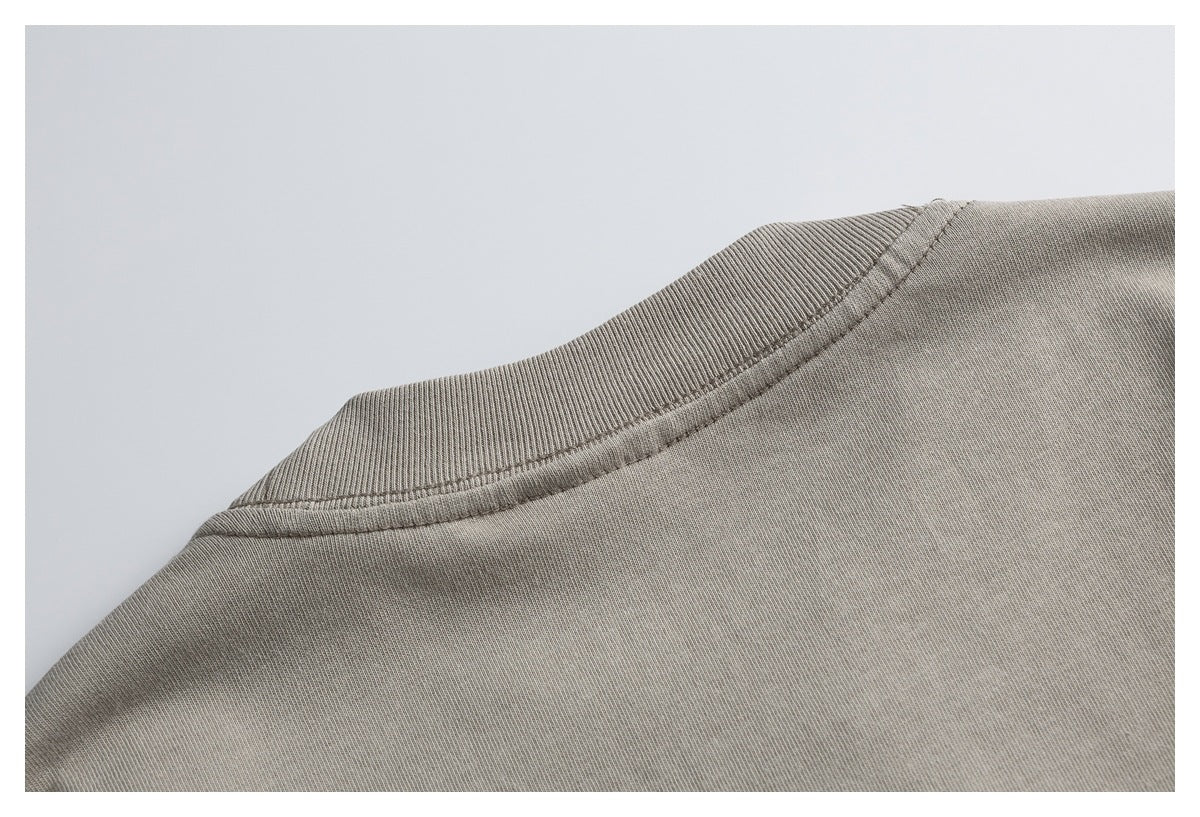Close-up of the back of a taupe T-shirt, showing its ribbed crew neckline and shoulder seams.