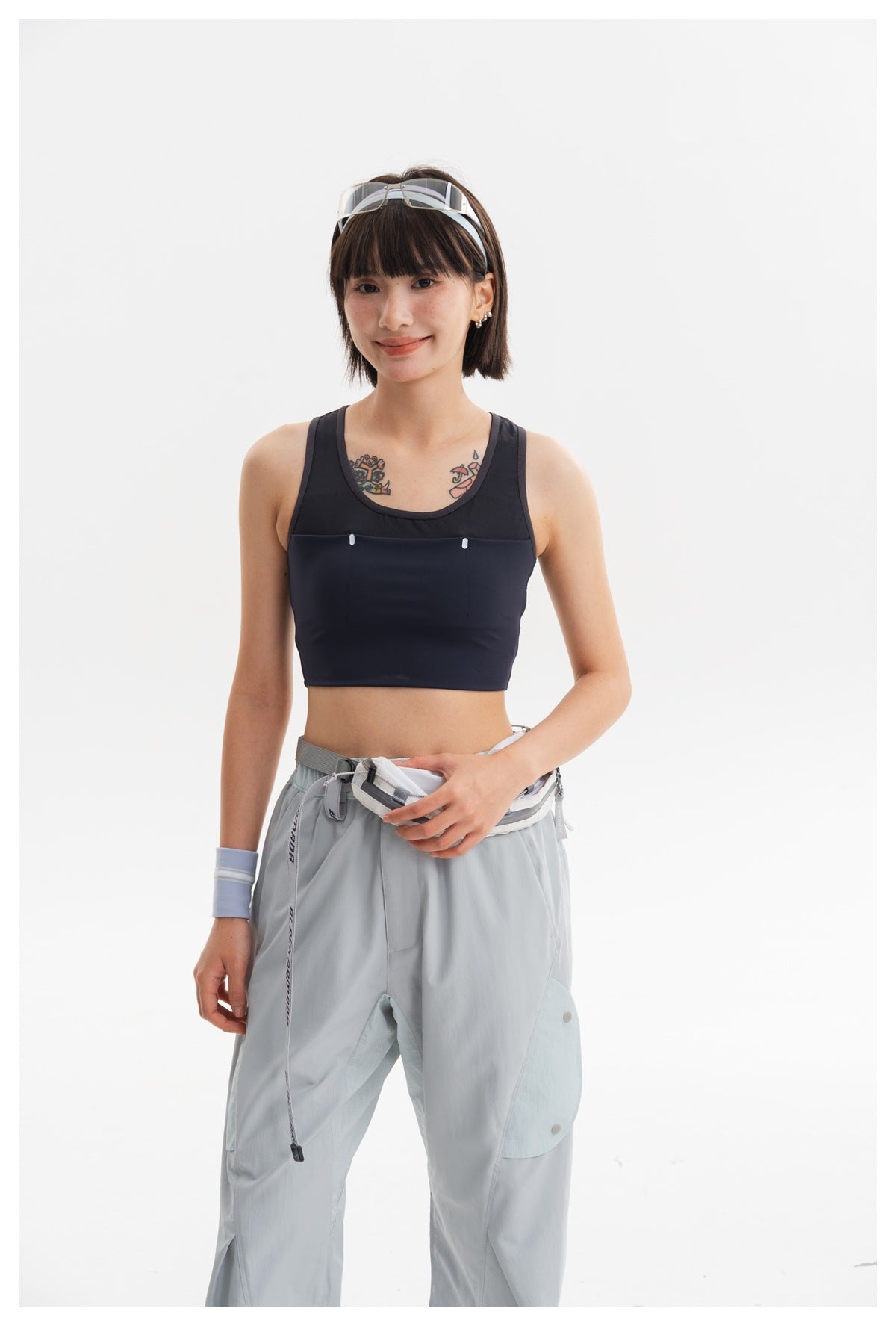 Model wearing a navy cropped tank and pale blue-gray cargo pants, shown from head to mid-thigh.