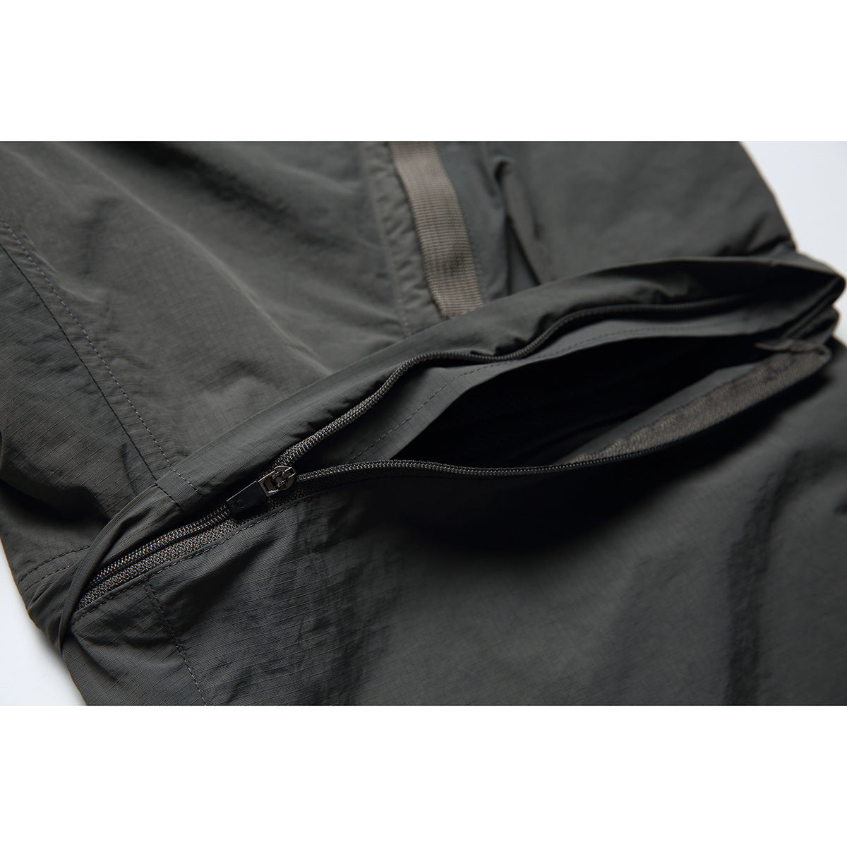 Close-up of dark pants with a partially open zippered pocket.