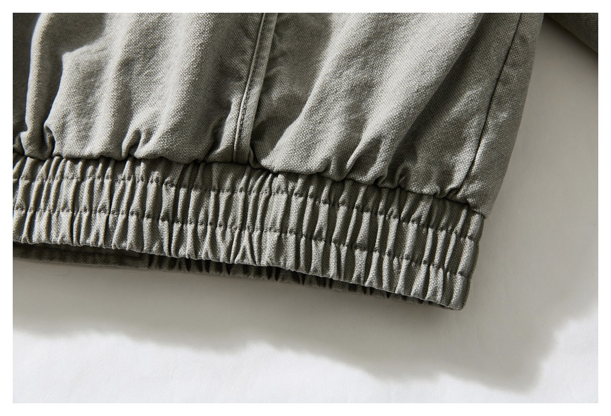 Close-up of a gray-olive woven garment with a wide gathered elastic hem.