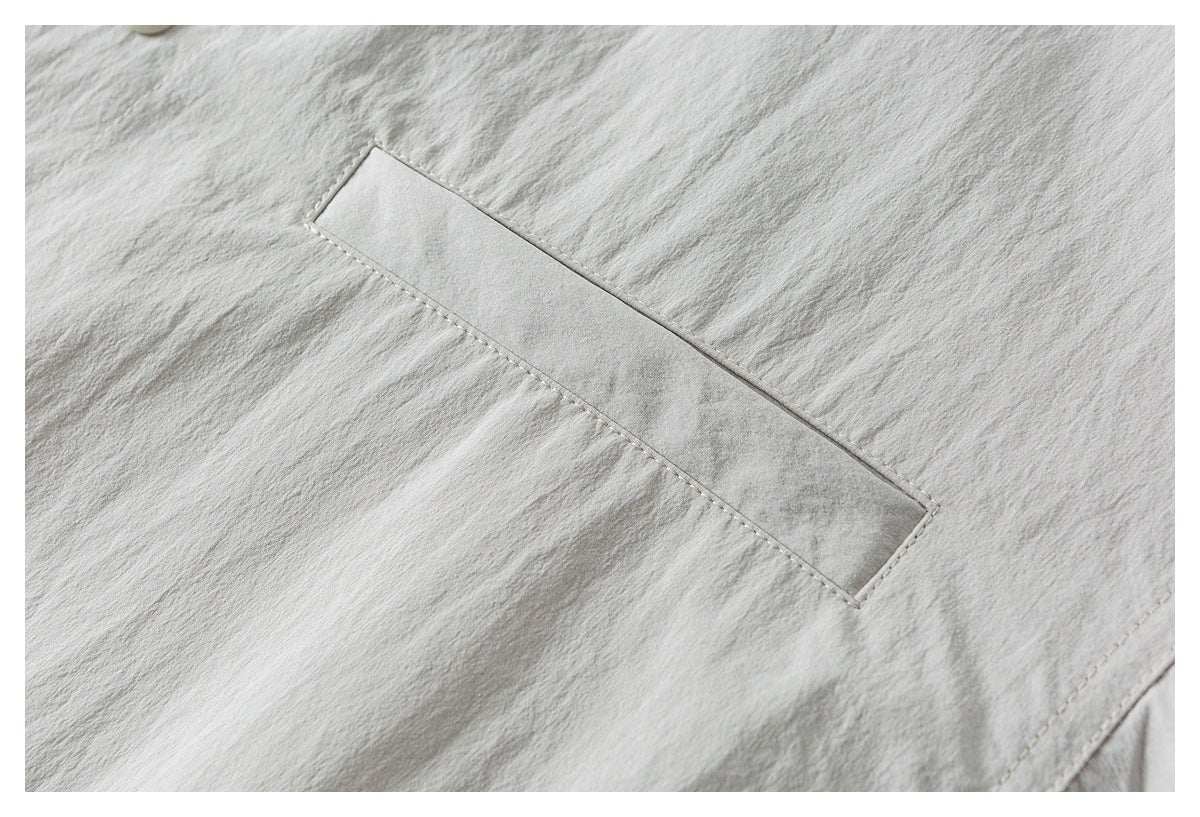 Close-up of a narrow rectangular welt pocket on light gray-beige fabric.