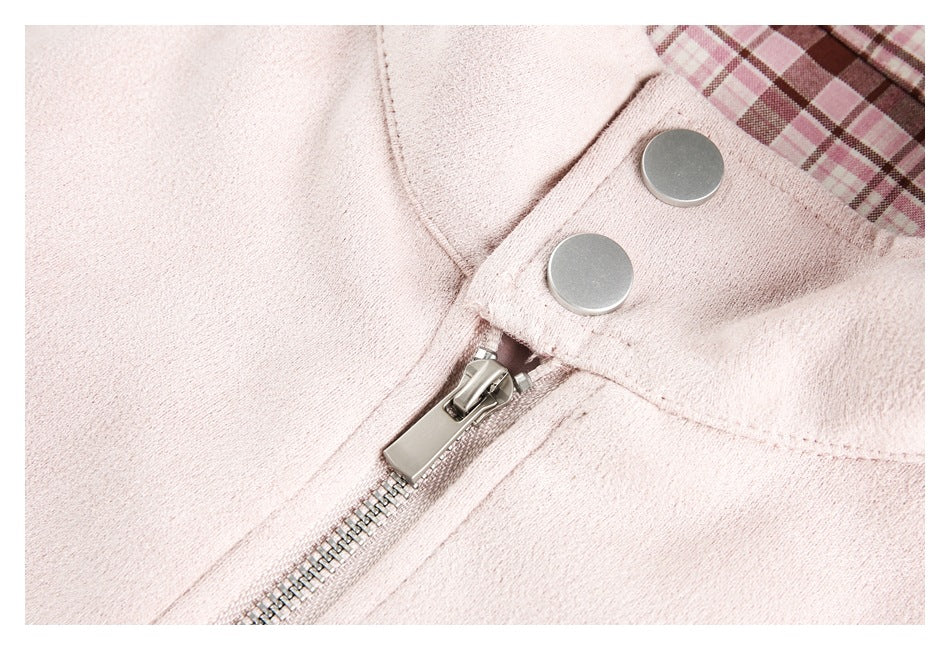 Close-up of a pale pink jacket zipper and snap-fastened flap beside the plaid lining.