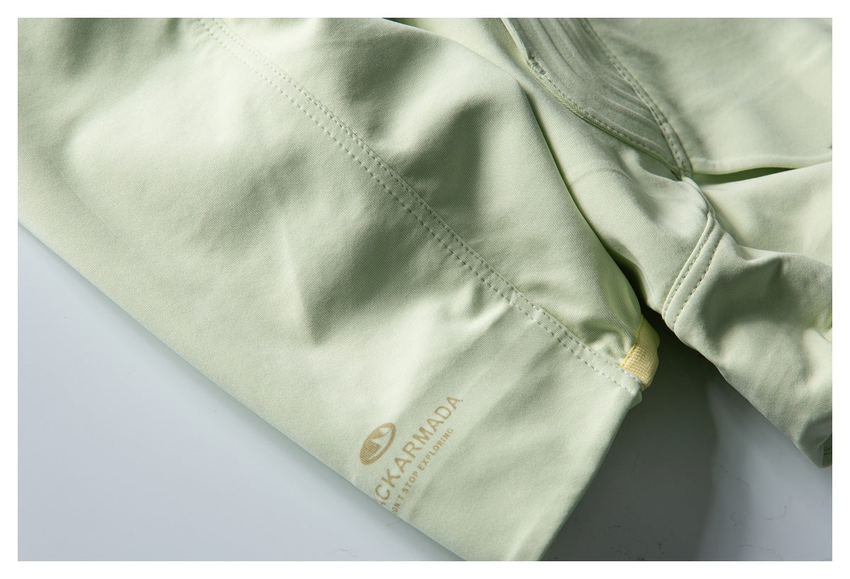 Close-up of a pale sage-green jacket sleeve cuff with tan Black Armada branding and stitched seams.
