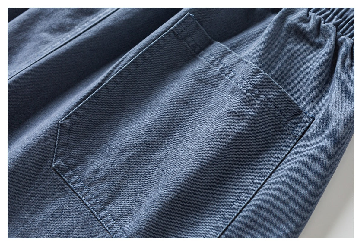 Close-up of a large stitched patch pocket on blue-gray pants.