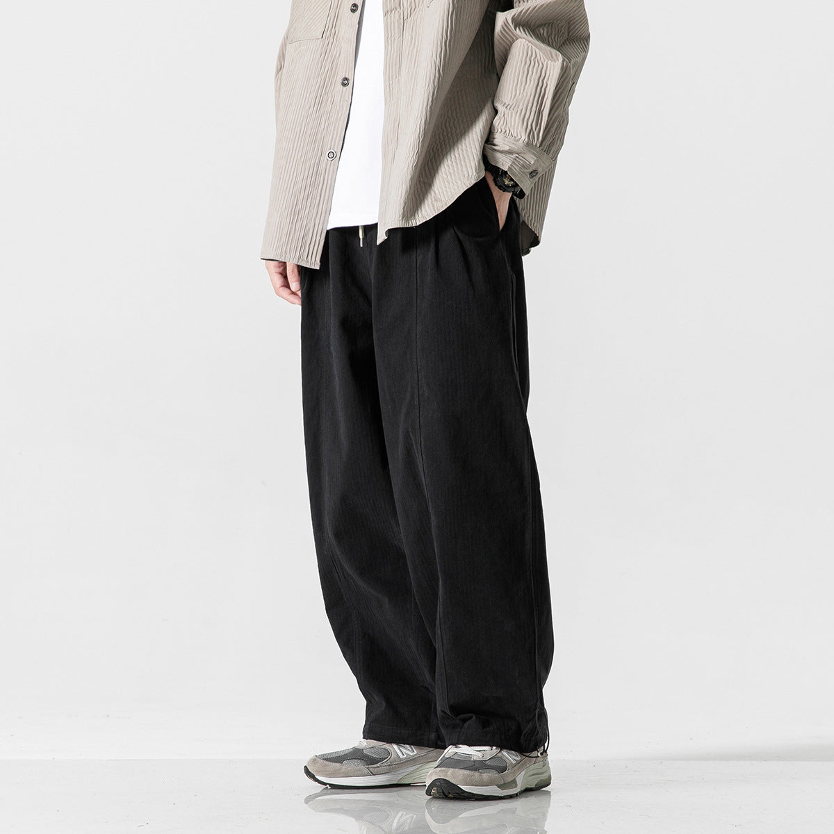 Cropped model wearing black wide-leg pants with a loose fit and adjustable hems.