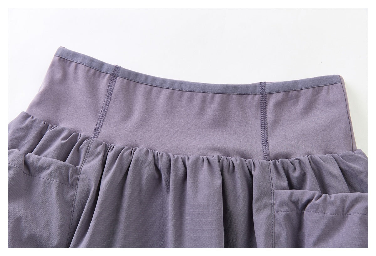 Close-up of the skirt’s waistband, stitched seams, and gathered upper panels in muted purple.