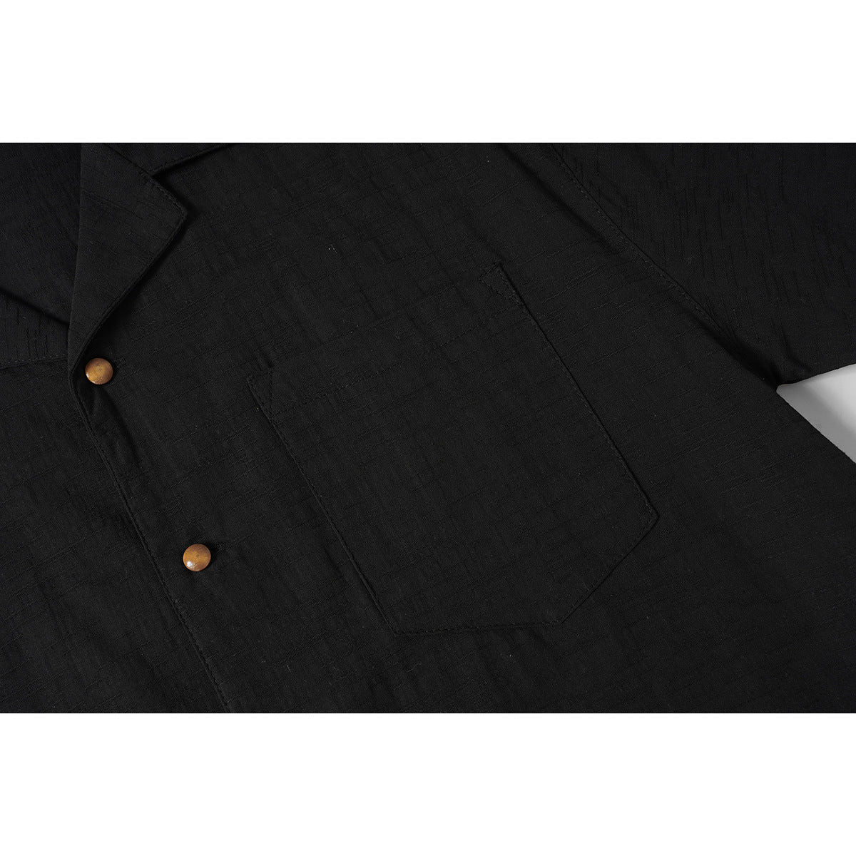 Close-up of a black shirt's chest pocket and front placket with two wood-tone buttons.
