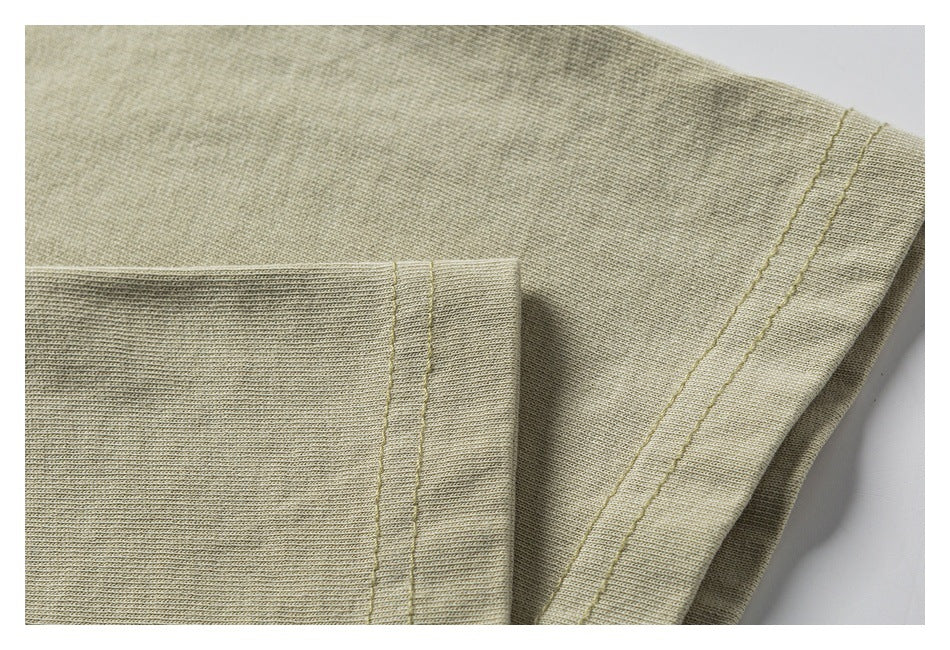 Close-up of beige knit garment fabric with parallel stitching along a folded edge.