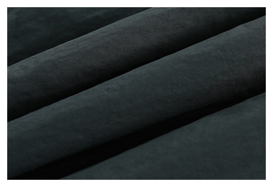 Close-up of dark charcoal fabric draped in soft folds, showing a fine textured surface.