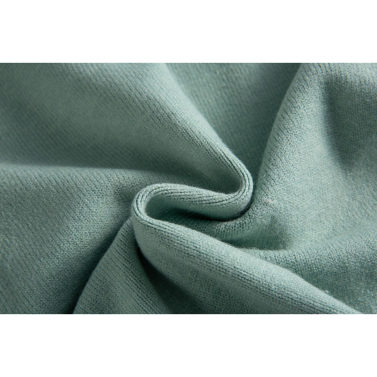 Close-up of pale mint-green knit fabric folded to show its texture and edge.