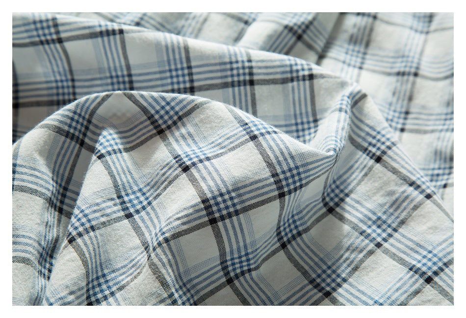 Draped close-up of white fabric with a blue and charcoal plaid pattern.