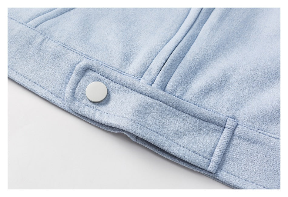 Close-up of a pale blue garment hem tab fastened with a white snap.