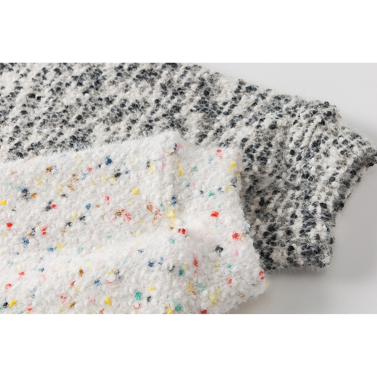 Close-up of a white fuzzy fabric with colorful flecks layered over black-and-white patterned fabric.