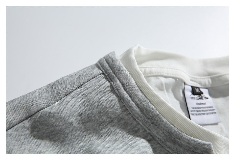 Close-up of the gray sweatshirt’s shoulder seam, collar, white inset neckline, and inner label.
