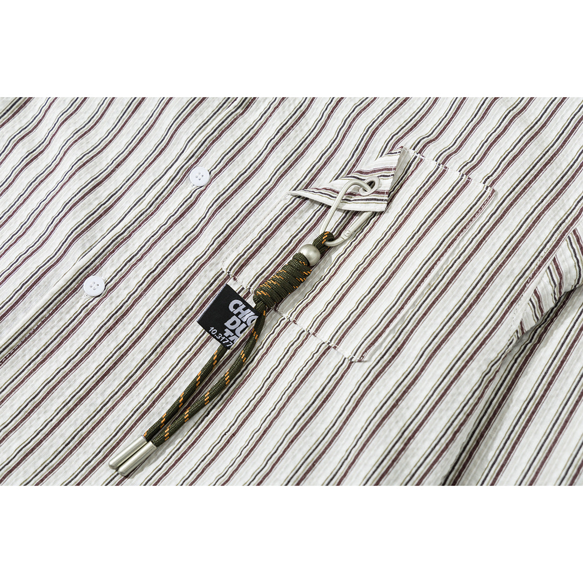 Close-up of a cream shirt with narrow dark stripes, a chest pocket, buttons, and a decorative cord detail.
