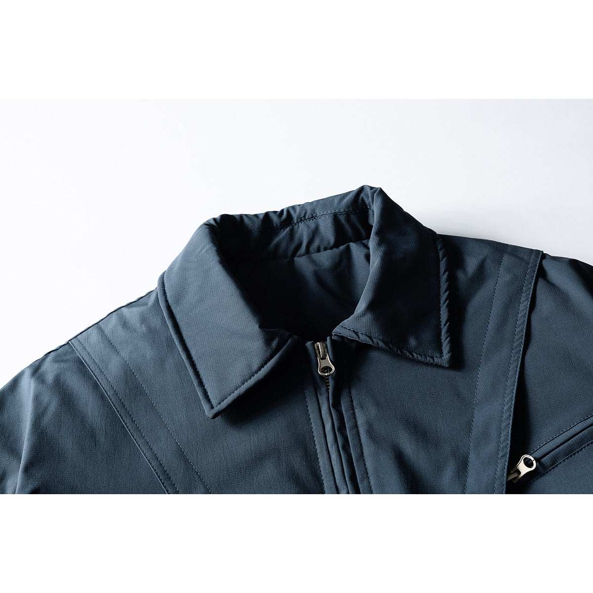 Close-up of a dark navy jacket collar, center zipper, stitched shoulder panels and a zippered chest pocket.