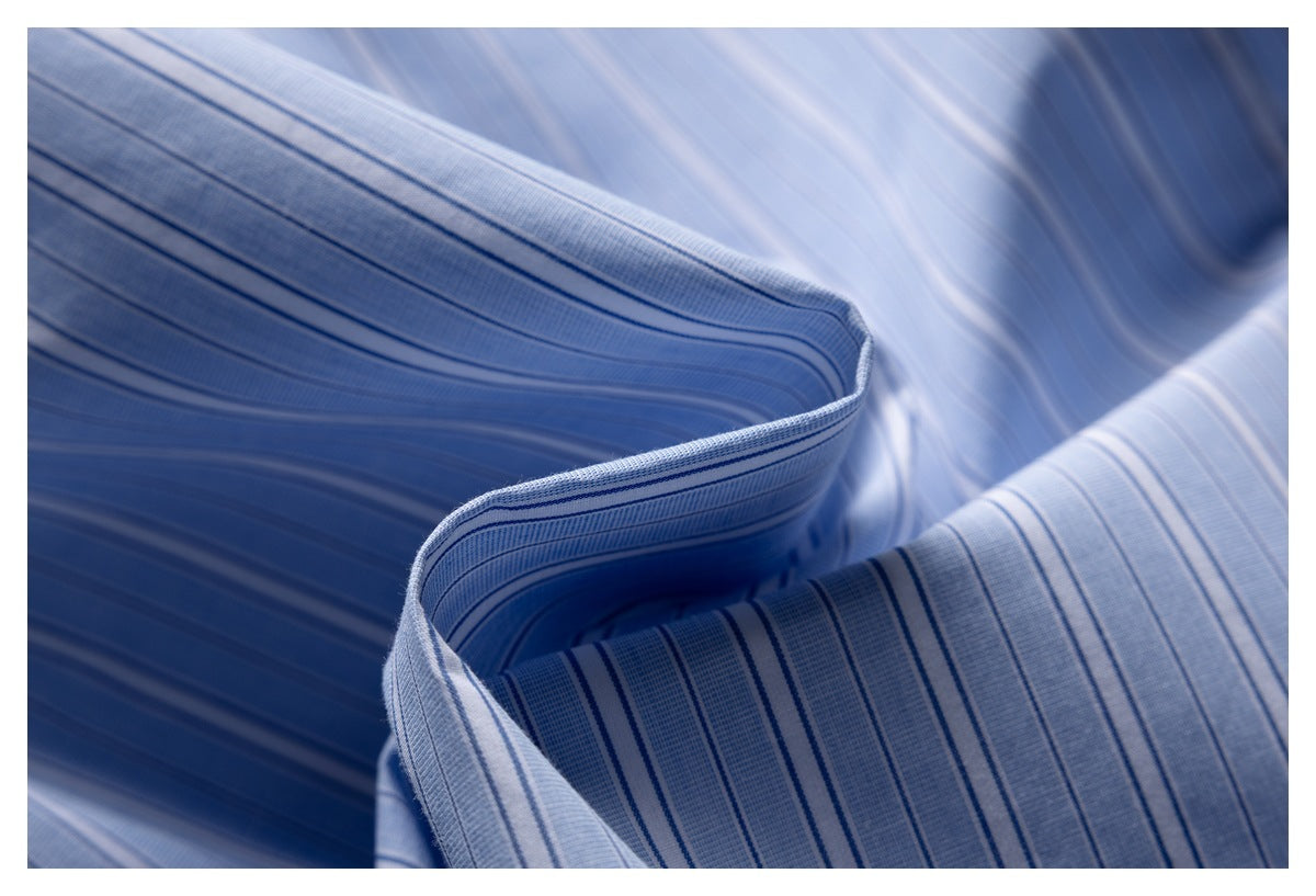 Macro view of light blue striped garment fabric, showing its pattern and finished folded edge.
