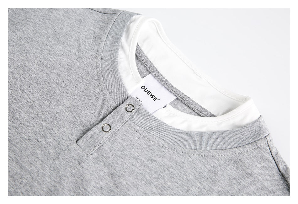 Close-up of a gray top's layered neckline, two metal snaps, and inside label.