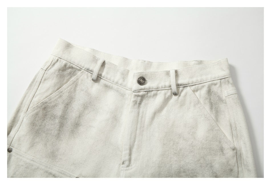 Close view of the pants’ front waistband, button, belt loops, angled pockets, and gray mottled finish.