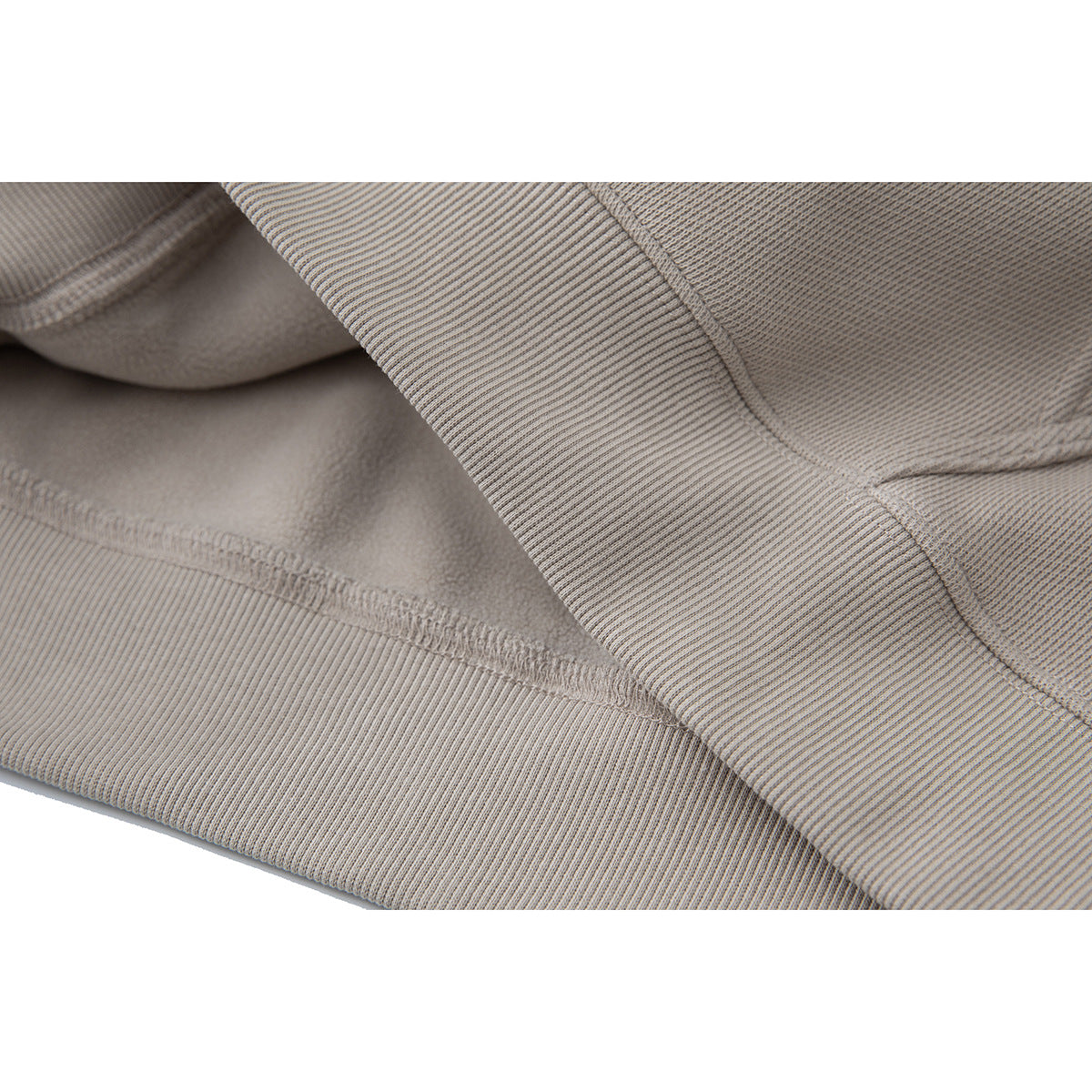 Close-up showing the ribbed cuff, stitching, and fabric texture of a light beige hoodie.