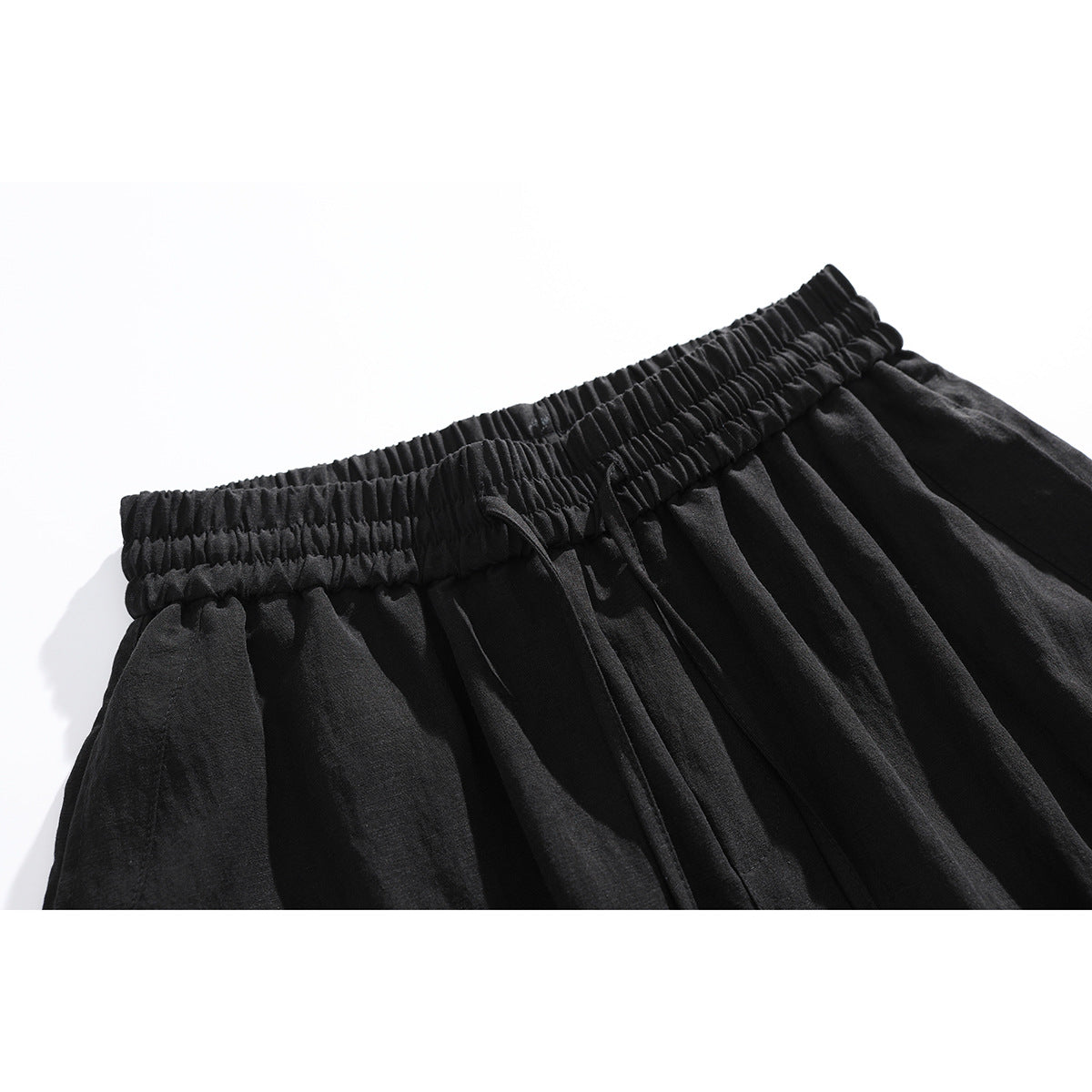 Close-up of black shorts showing the gathered elastic waistband and drawstring.