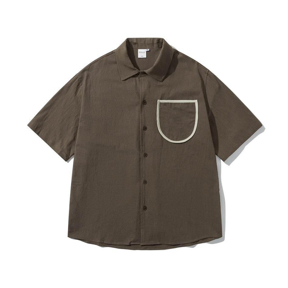 Brown short-sleeve button-up shirt with a large U-shaped chest pocket trimmed in cream piping, flat lay