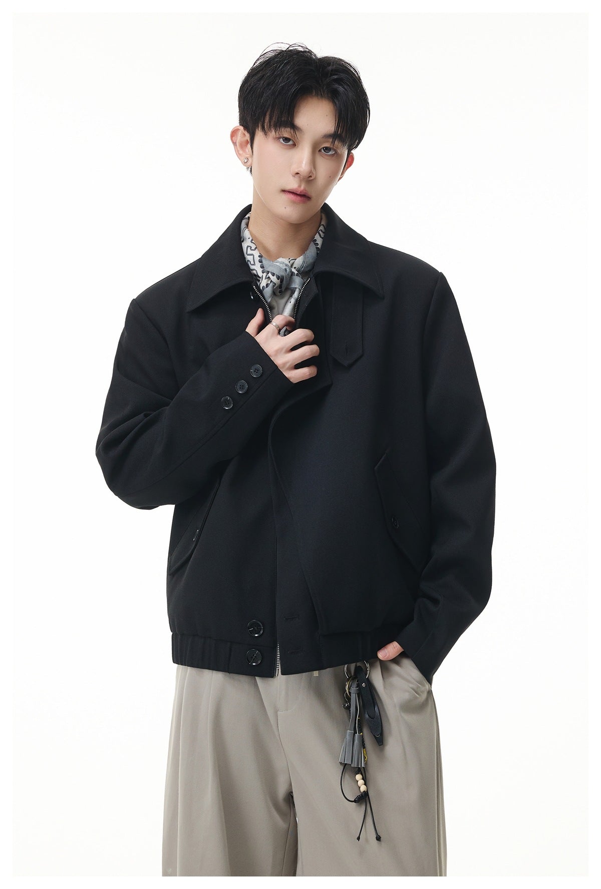 Model wearing a black jacket with a wide collar and angled pockets, styled with a patterned neck scarf.