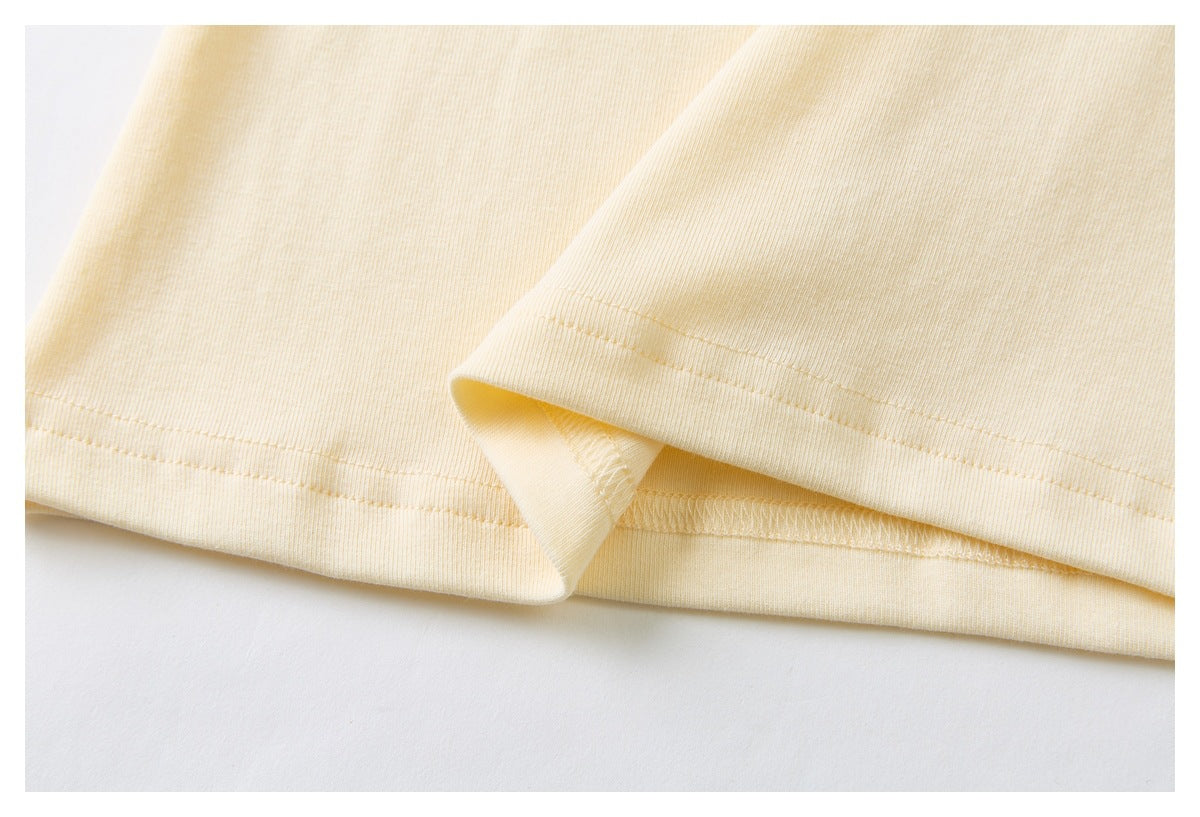 Close-up of the cream shirt's double-stitched bottom hem and overlocked seam.