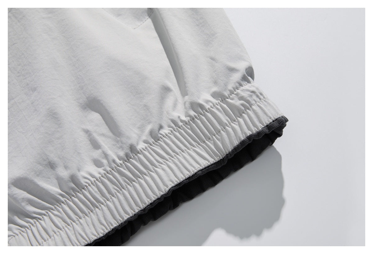 Close-up of a gathered elastic hem on a light gray garment, with dark fabric visible underneath.